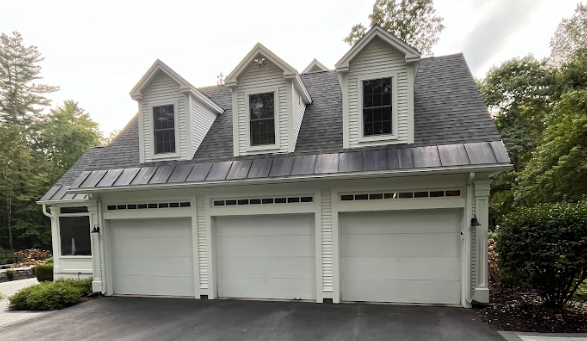 A white house with three garage doors and a gray roof.