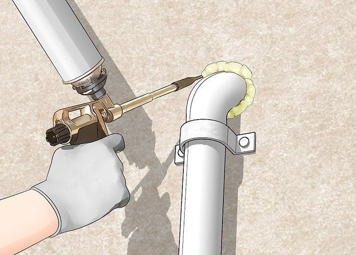 Gloved hand using a torch to solder a metal pipe joint with yellow sealant on a white pipe.