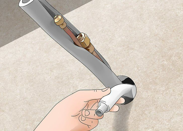 Hand holding a white handle attached to a curved gray blade with brass fittings on a light surface.