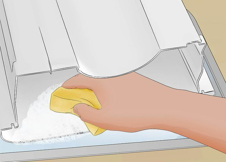 Hand wiping a white appliance interior with a yellow cloth