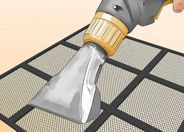 Hand tool scraping gray material from a mesh screen surface