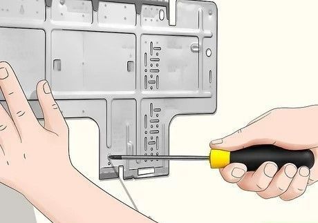 Hands holding a screwdriver and a metal panel being adjusted during installation