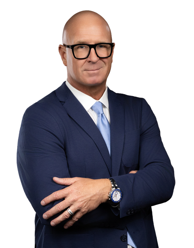 Studio portrait of a bald man in a navy suit, glasses, and light blue tie with arms crossed.