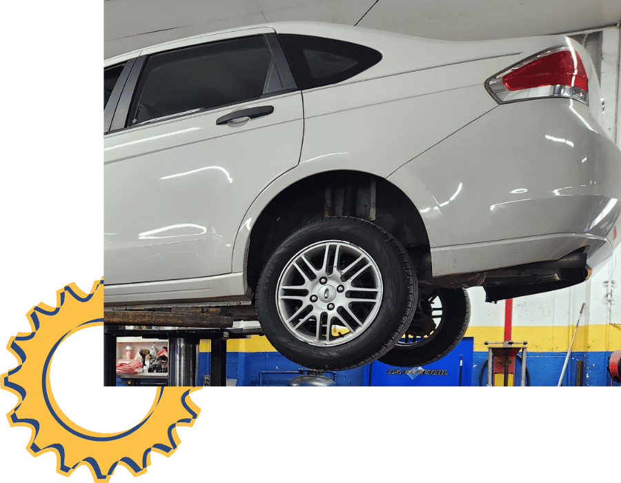 White vehicle on lift in auto repair shop for inspection and maintenance service.