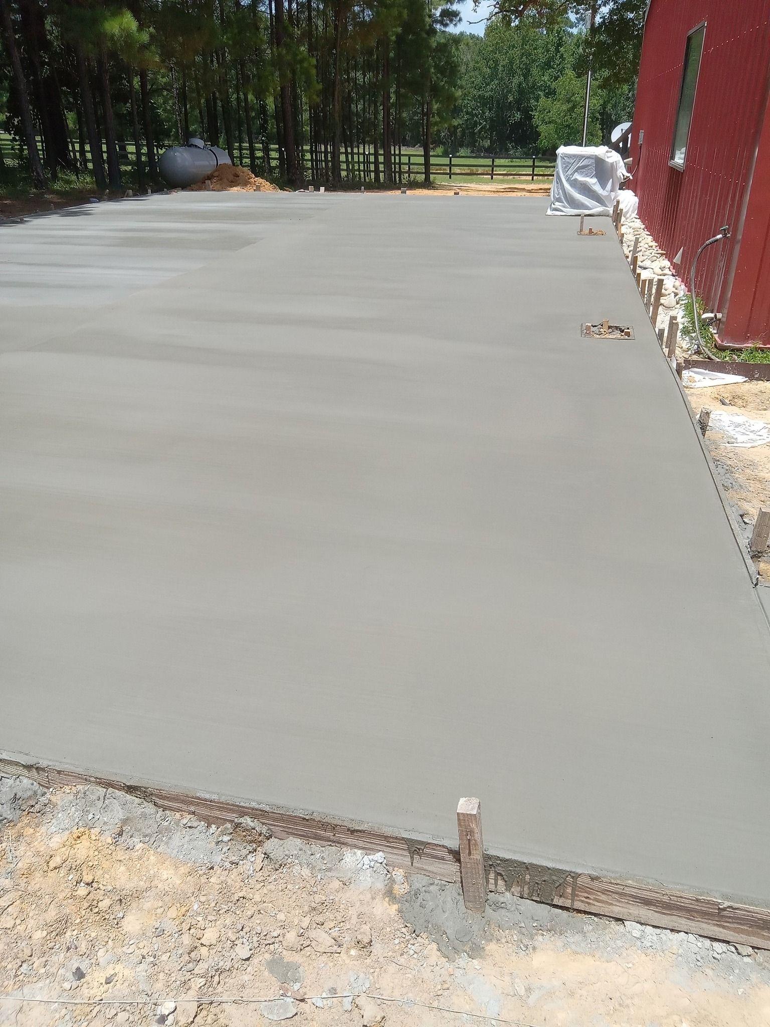 Freshly poured concrete driveway next to a brick building.