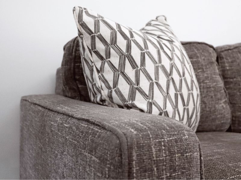 Gray patterned pillow on a brown fabric sofa