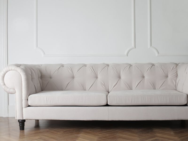Cream tufted sofa against a white paneled wall in a minimalist room