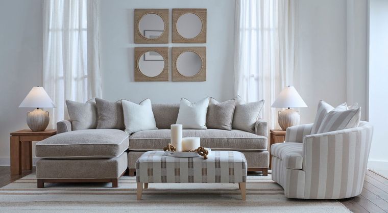 Bright living room with beige sofa, striped armchair, coffee table, and white curtains.