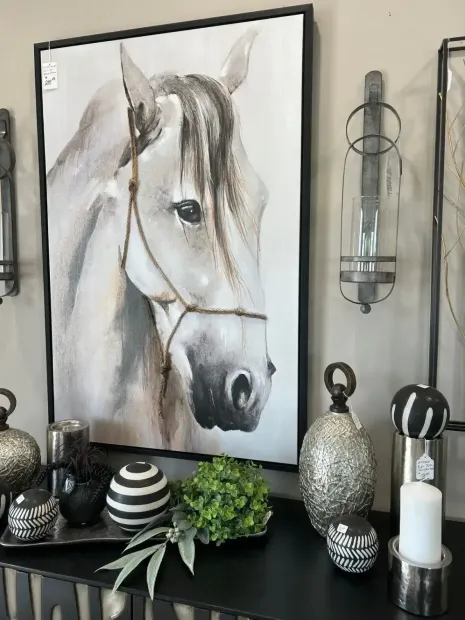 Framed horse portrait above a mantel with black-and-white decor and greenery