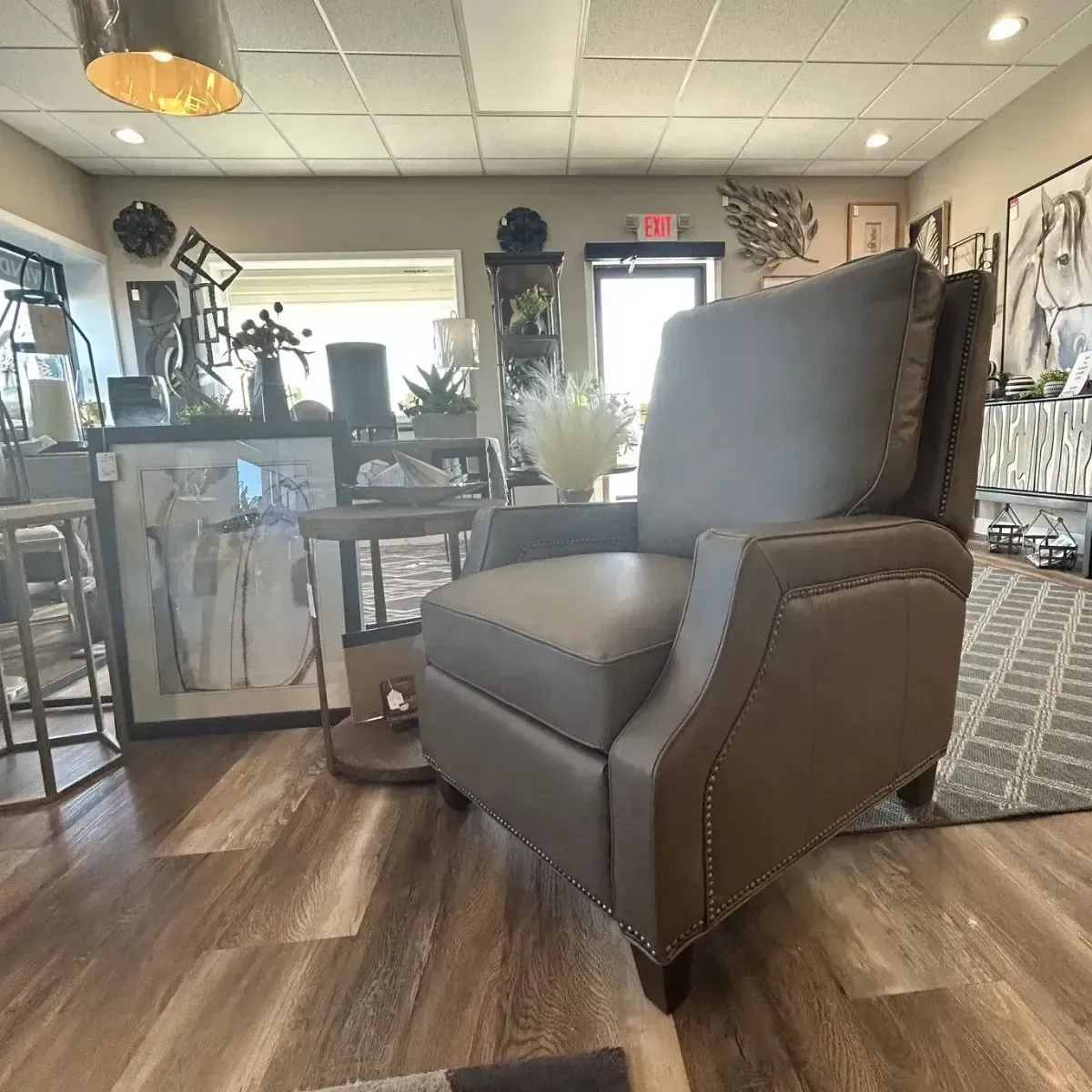 Modern boutique interior with a gray chair, wood floors, and decorative furnishings near a bright entrance