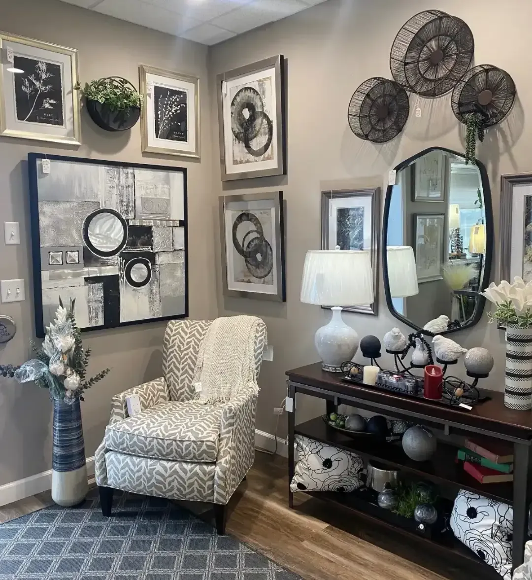 Cozy living room corner with patterned chair, mirror, wall art, and black console table with lamp and decor