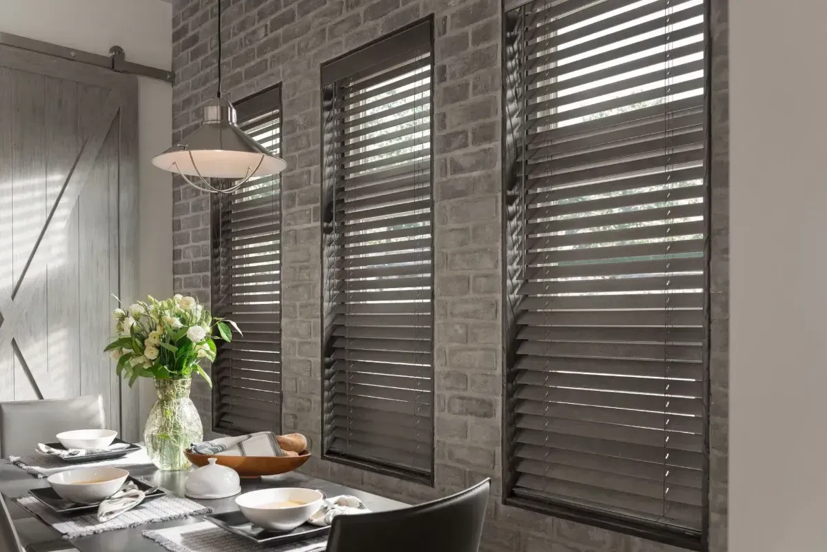Sunlit window with closed white blinds casting shadows on a cream wall