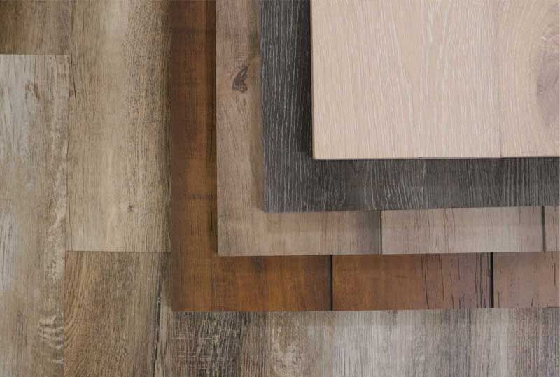 Overlapping wood sample boards in gray, brown, and beige tones on a textured background