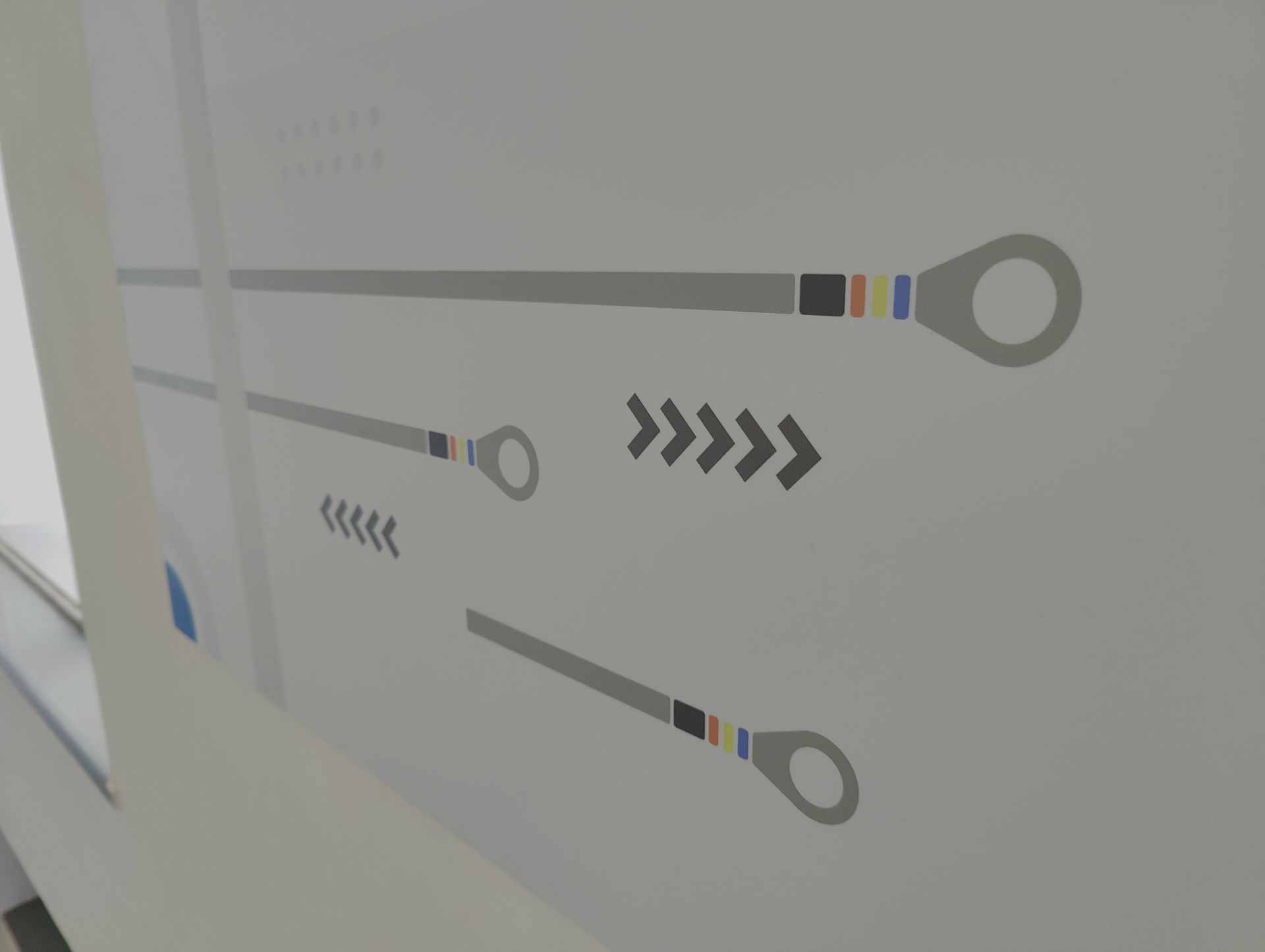 Abstract wall graphic with gray lines, chevrons, and colorful ring shapes on a light wall