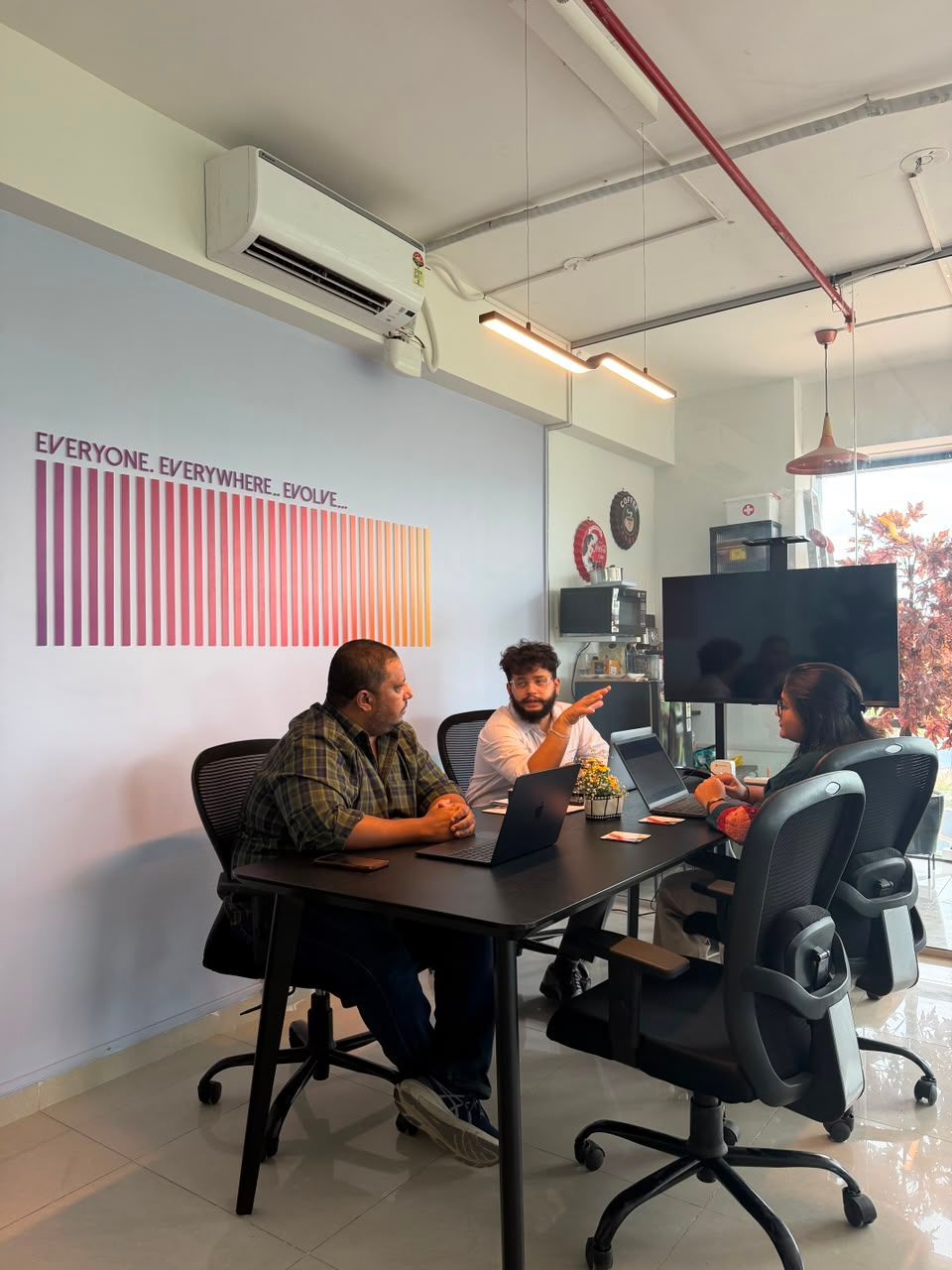 Two people working on laptops at a conference table in a modern office room