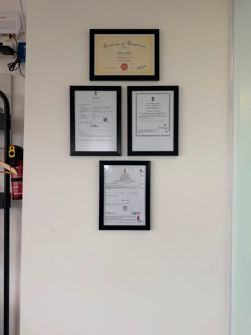 Framed certificates and awards arranged on a white wall above a doorway