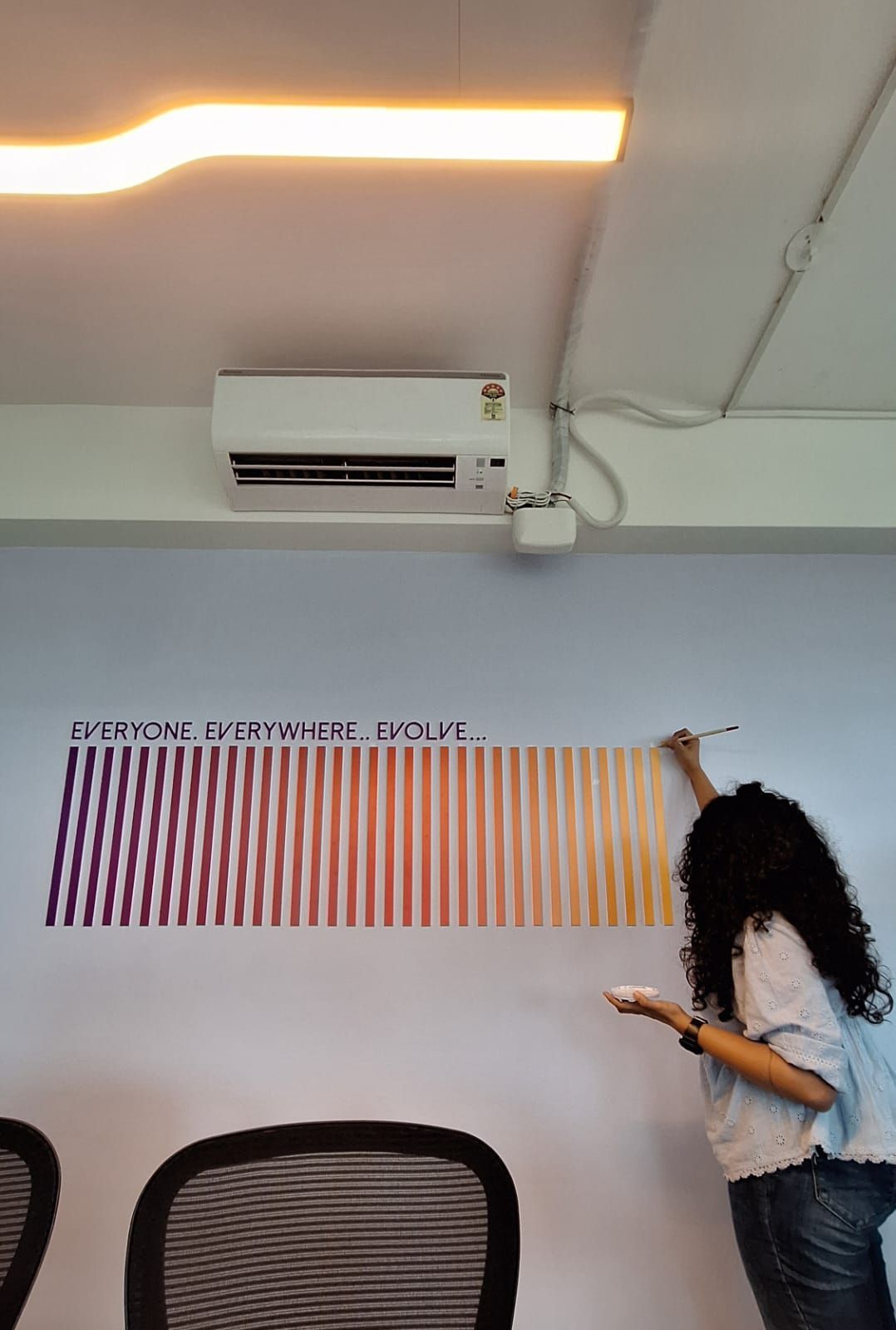 Person in a room pinning orange strips to a wall chart under an air conditioner.