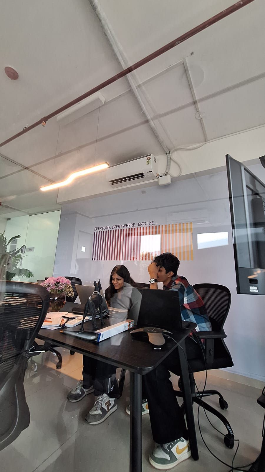 People seated at a conference table in an office meeting room, with laptops and papers.