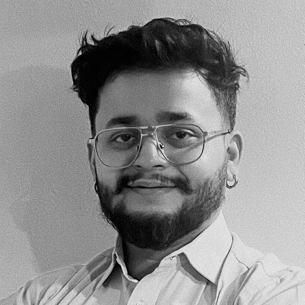 Portrait of a man with glasses and a beard, wearing a light shirt, looking at the camera