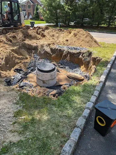 Large backyard excavation with exposed dirt, a concrete utility pipe, and an excavator in the background.