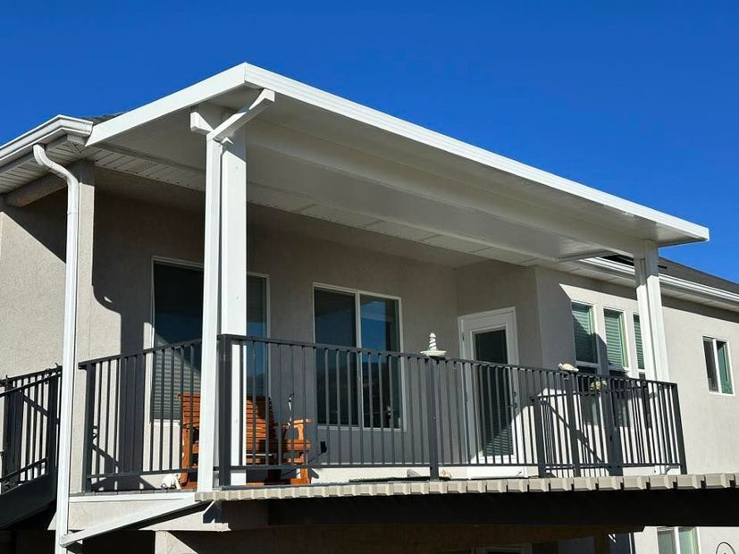 Exterior of a modern beige house with a black-railed balcony under a clear blue sky