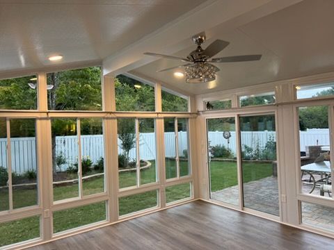 Sunroom with large windows, ceiling fan, and sliding door opening to a fenced backyard and patio