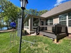 House entrance with a small porch, ramp, and lamp post beside a grassy yard on a sunny day