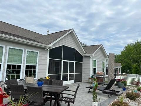 Back patio with outdoor dining set, lounge chairs, and screened porch on a suburban house