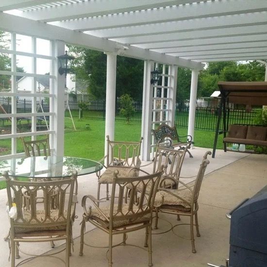 Covered patio with wicker chairs and tables overlooking a green backyard and gazebo