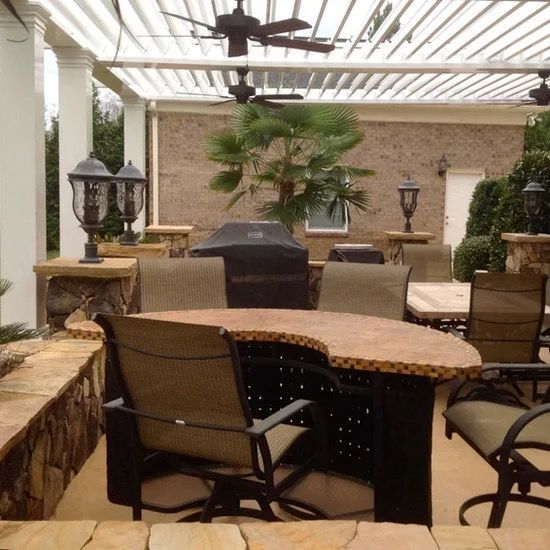 Covered patio with wicker chairs, stone table, and potted plants in an outdoor seating area