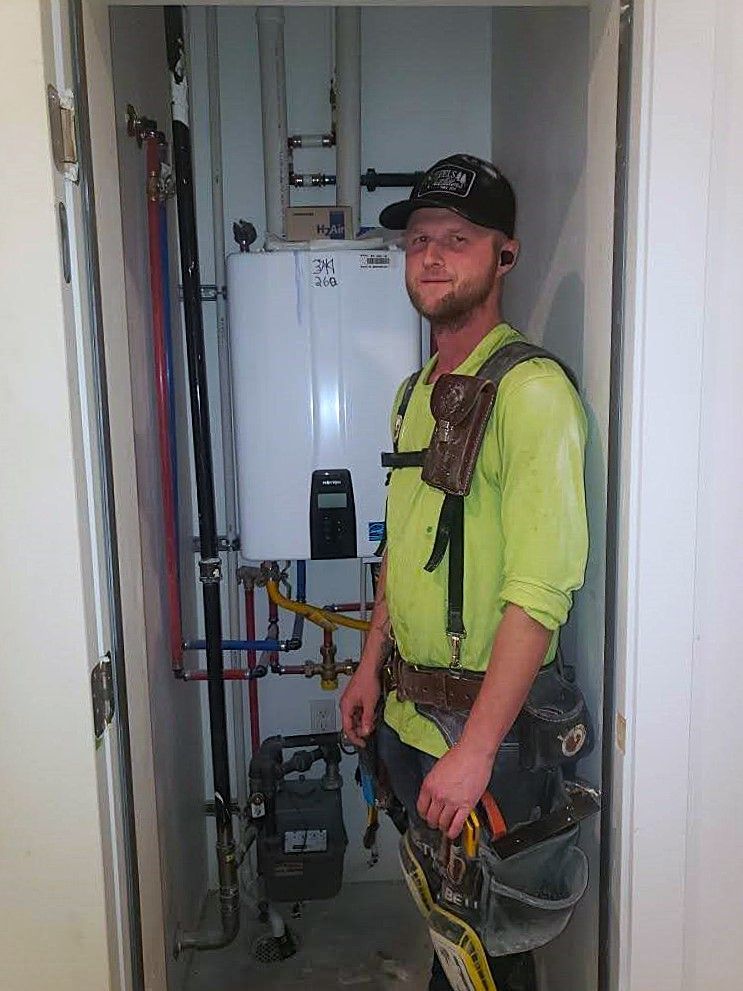 Licensed Sharp Water Solutions technician performing water heater replacement in Sandy UT home, code-compliant install