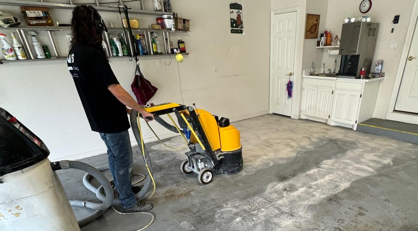 Person using a yellow concrete grinder to prep a garage floor for epoxy