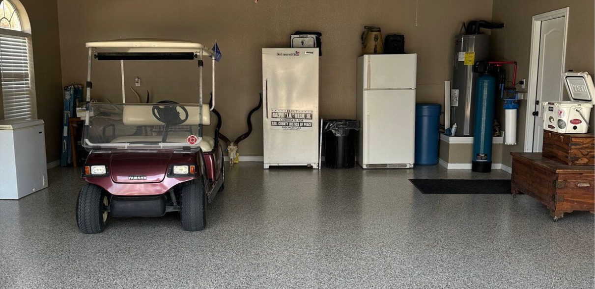 A garage with a golf cart, two refrigerators, and storage, with a speckled floor.