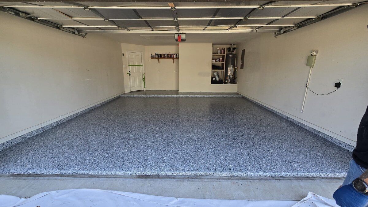 Empty garage with a gray speckled epoxy floor and white walls.