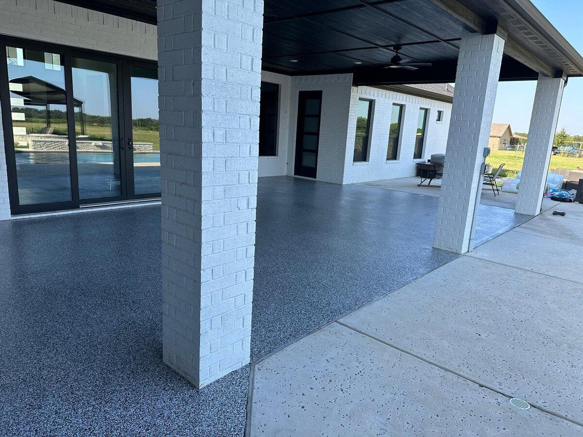 Exterior view of a home's covered patio with epoxy flooring, and support columns