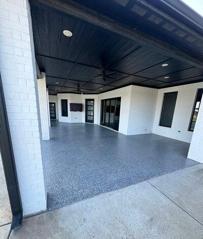 Covered patio with black ceiling and gray speckled floor.