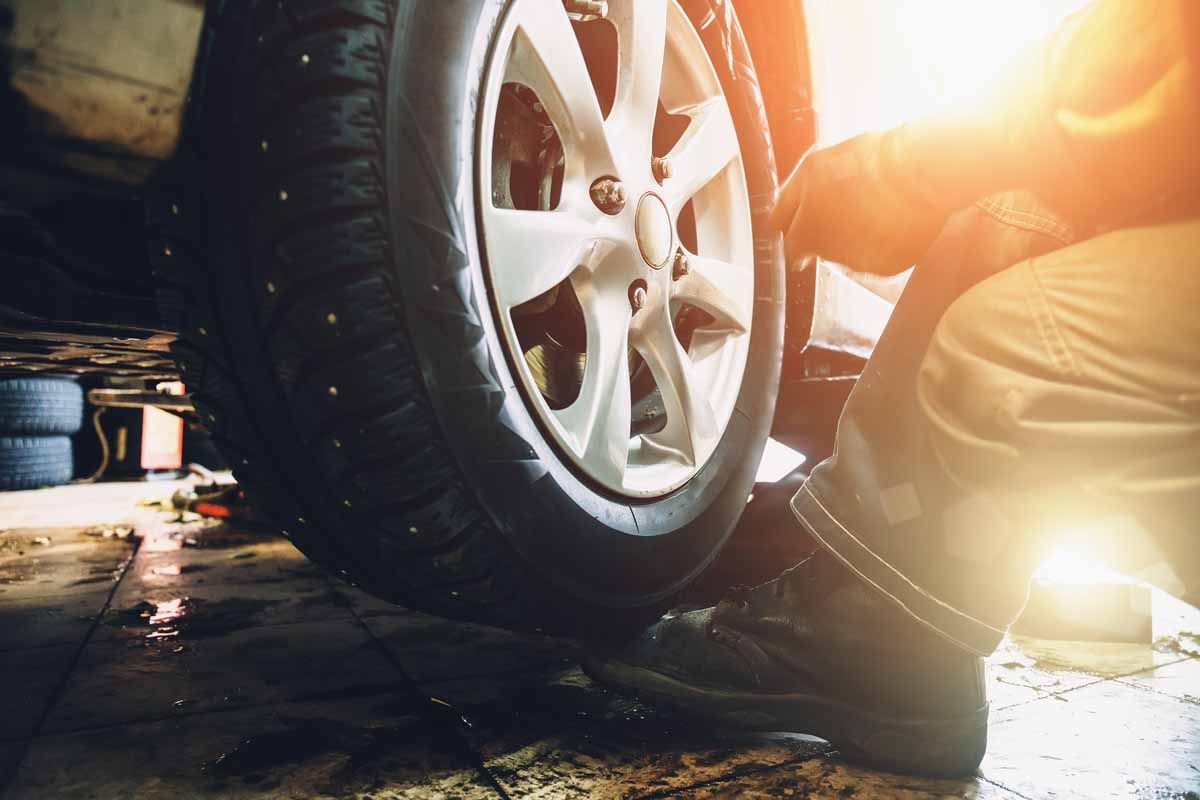 A man is changing a tire on a car in a garage.