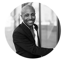 A man in a suit and tie is smiling in a black and white photo.