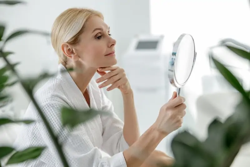 Woman Smiling in Front of Mirror — Dearborn, MI — Masri Clinic Woman Smiling in Front of Mirror — Dearborn, MI — Masri Clinic