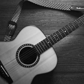 Black-and-white acoustic guitar on a wooden surface with a strap attached