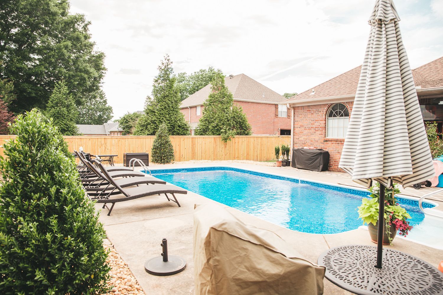 There is a large swimming pool in the backyard of a house.