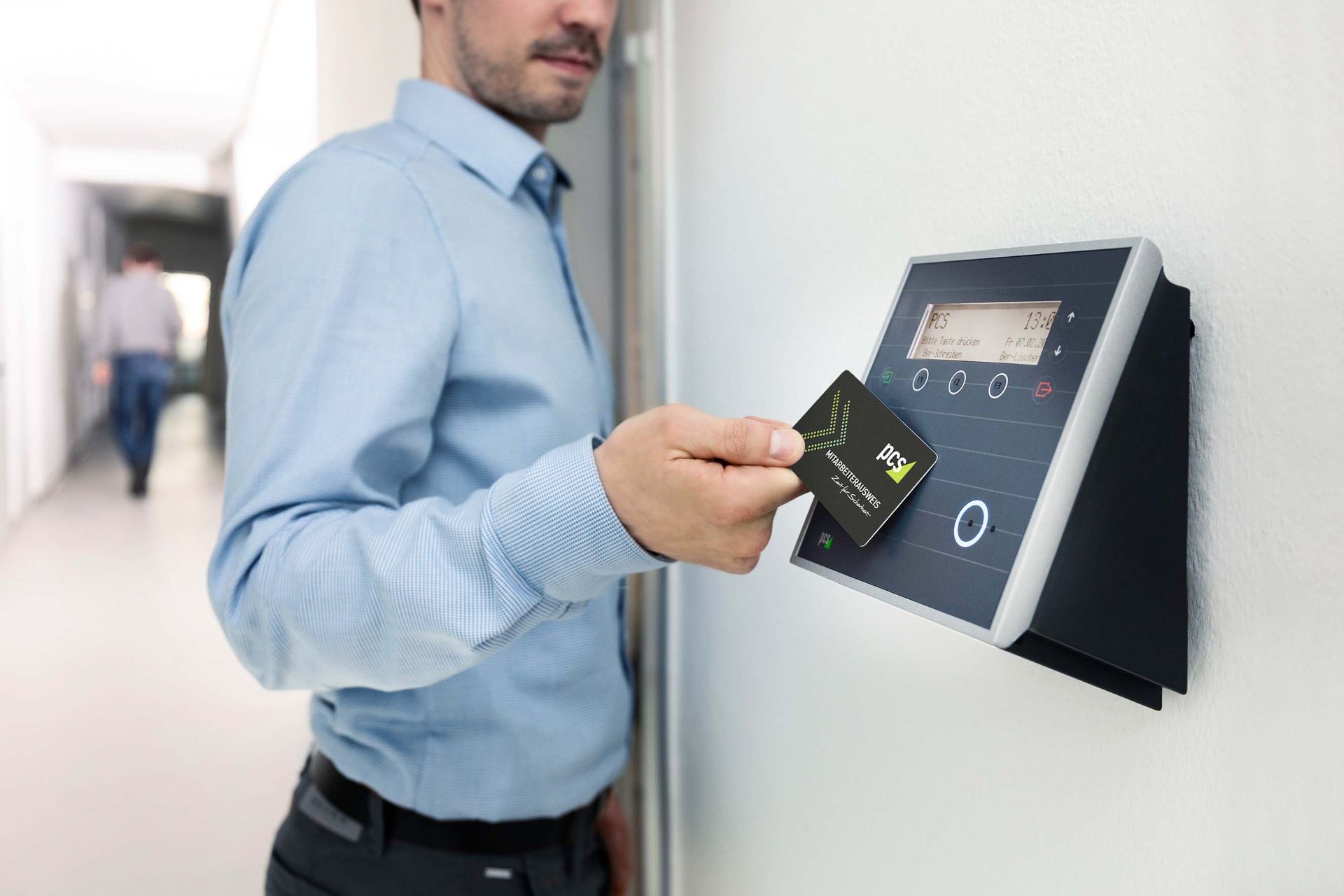 A man in a blue shirt uses a key to open a metal cabinet door.