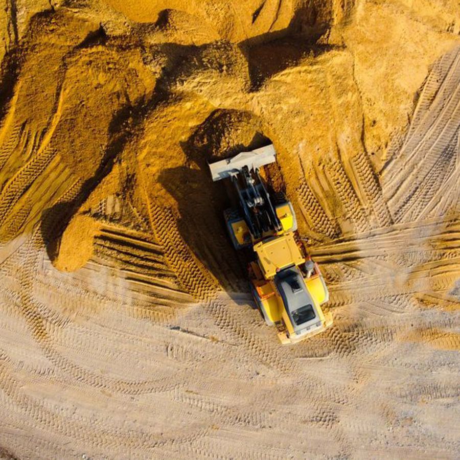 Top-down view of a yellow dump truck unloading sand at a construction site