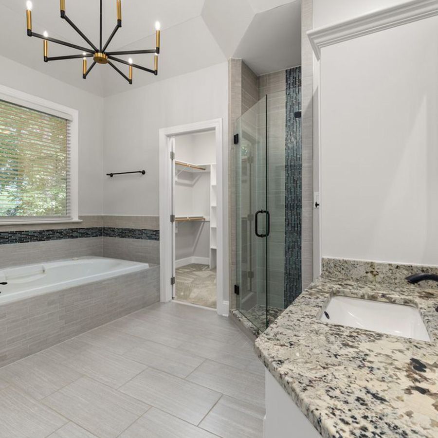 Modern bathroom with freestanding tub, glass shower, white tile, and granite vanity countertop.
