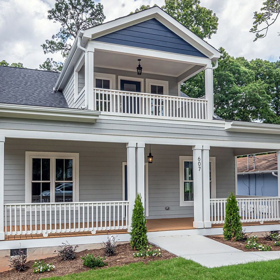 Two-story gray house with white porch railings, blue gable, and landscaped front walkway