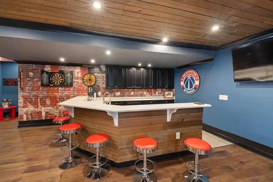 Empty sports bar with red stools, pool table, blue walls, and wall-mounted TV.