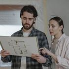 Two people reviewing a floor plan together indoors