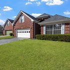 Brick suburban house with a white garage, large windows, and a green lawn under a blue sky