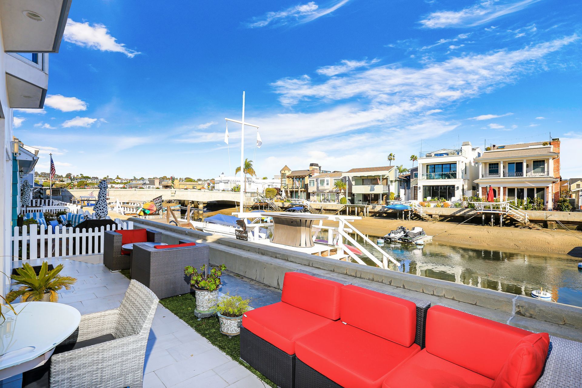A red couch is sitting on a patio next to a body of water.
