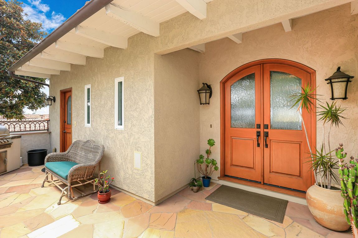 The front door of a house with a couch and chair in front of it.